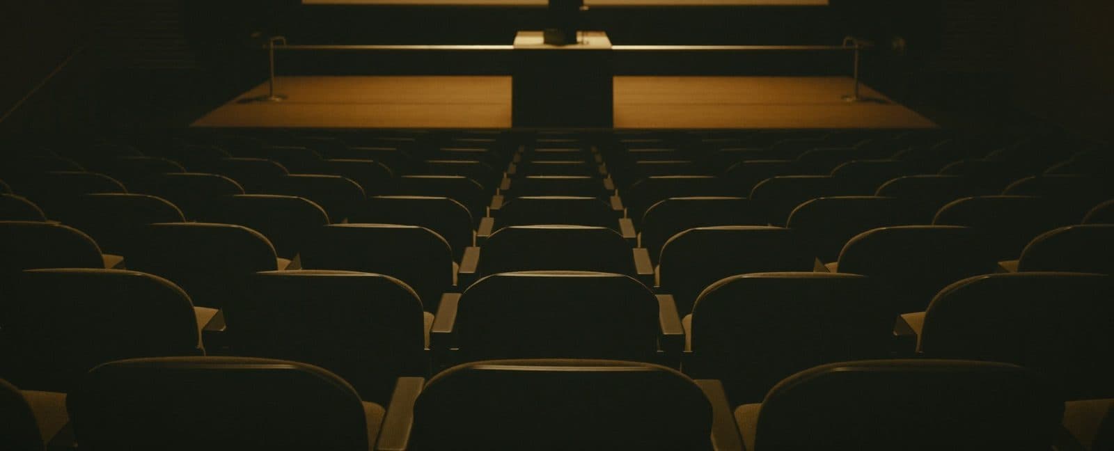 Dark university lecture hall lit by warm stage light