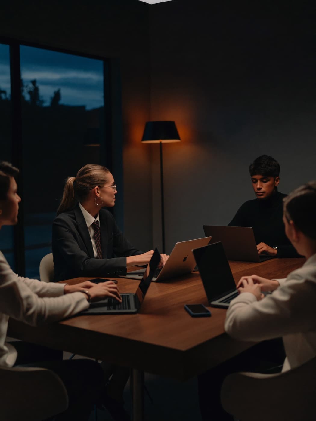 Team in a dark conference room discussing around a table in warm light