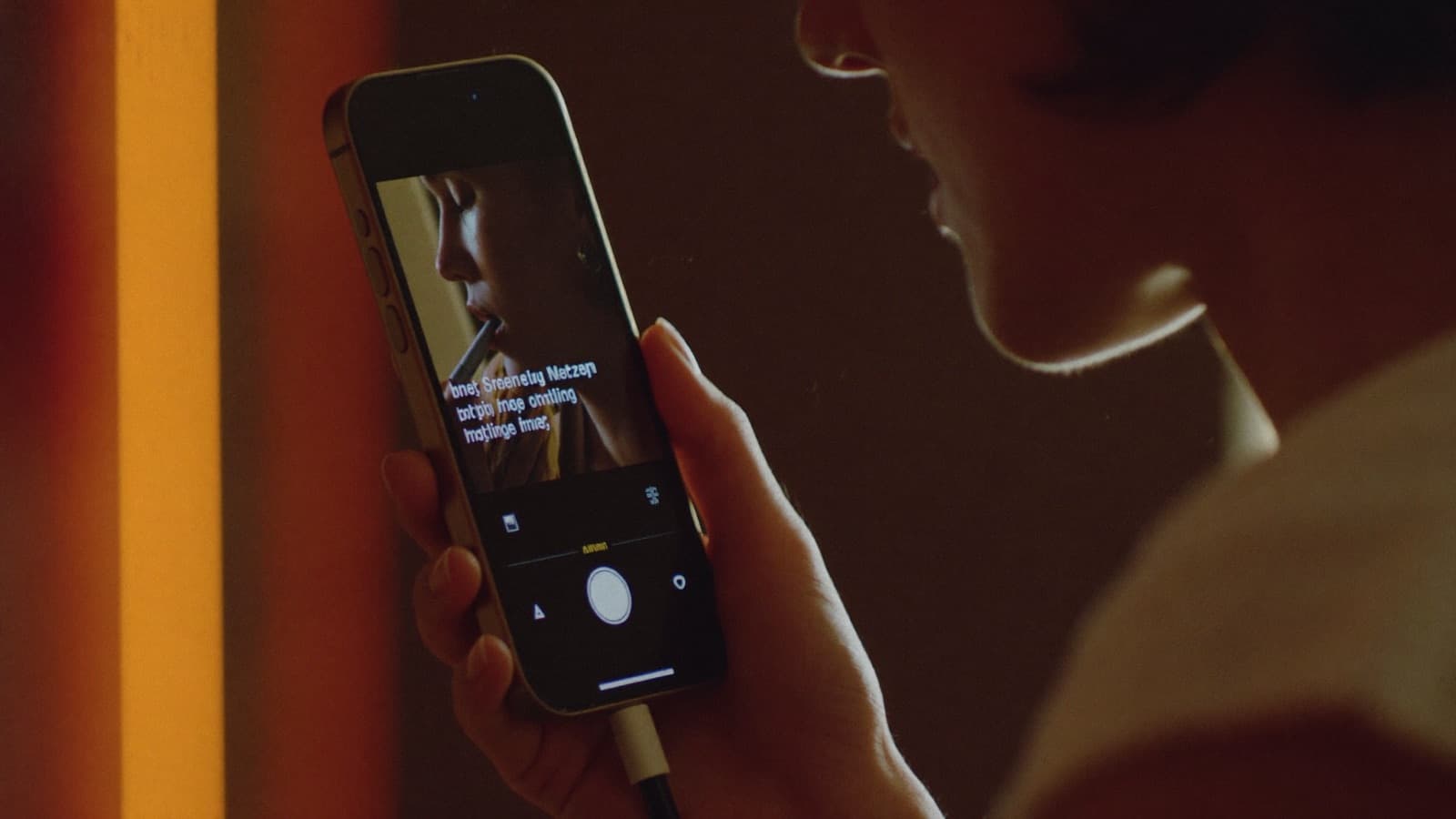 Person recording a voice memo into their phone in warm low light